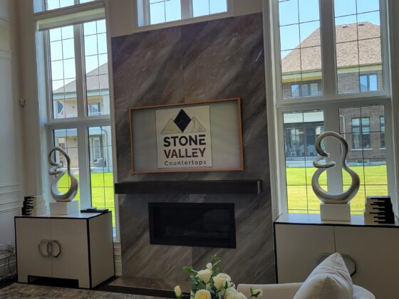 Luxury stone fireplace with custom Stone Valley Countertops branding in a modern living space, featuring elegant décor and natural lighting.