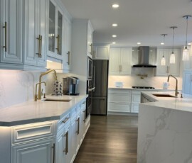 Spacious white kitchen featuring Calacatta quartz countertops and backsplash, a quartz waterfall island, gold hardware, glass-paneled cabinets, and modern pendant lighting.