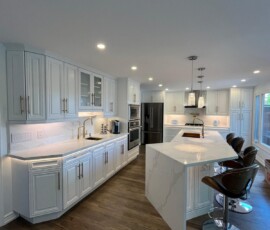 A modern kitchen showcasing white Calacatta quartz countertops with striking veining, paired with white cabinetry, stainless steel appliances, and a spacious island with bar stools