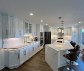 A modern kitchen showcasing white Calacatta quartz countertops with striking veining, paired with white cabinetry, stainless steel appliances, and a spacious island with bar stools