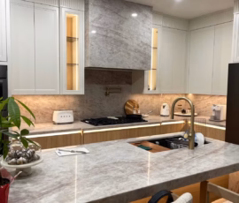 Modern kitchen with Taj Mahal Quartz countertops, gold faucet, and light cabinetry.
