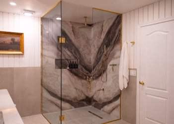 Full view of a luxury shower with Lyra quartz bookmatched walls, gold fixtures, and clear glass enclosure.