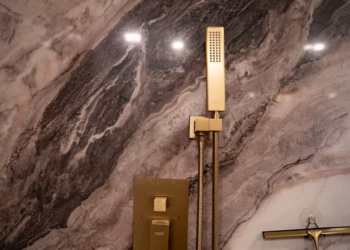 Detailed view of Lyra quartz shower wall highlighting rich veining and modern gold fixtures.
