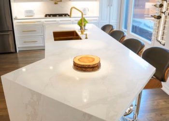 Calacatta Oro quartz kitchen island showing soft gold veining and a seamless polished surface.