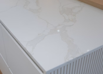 Detail view of a Calacatta Oro Quartz island top with soft gold veining paired with a raised butcher block section, installed by Stone Valley Countertops.