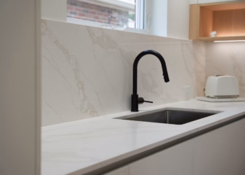 Calacatta Oro Quartz countertop and full-height backsplash with an undermount sink and matte black faucet installed by Stone Valley Countertops.