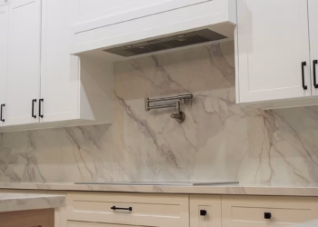 Lupas quartz full-height backsplash with natural veining behind a cooktop in a modern white kitchen.