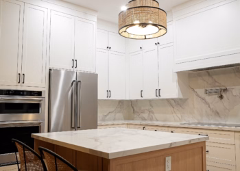 Lupas quartz kitchen island with matching countertops and full-height backsplash beside stainless steel appliances in a modern white kitchen.